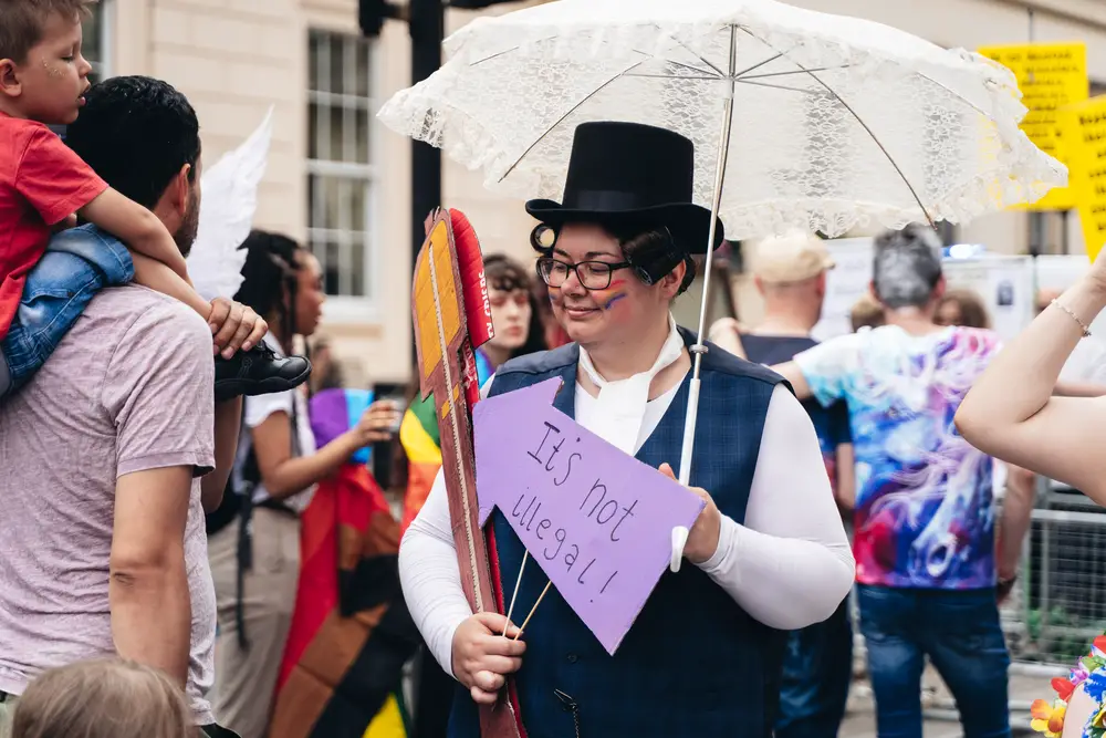 woman-with-white-umbrella-and-others-holding-flags-and-banners-at-a-pride-march