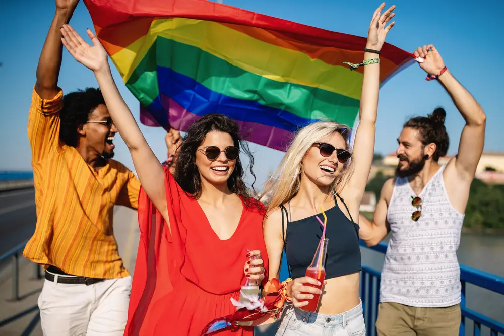 four-happy-friends-holding-pride-flag-outdoors