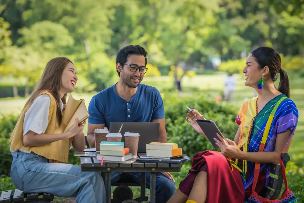 group of smiling students enrolled at an lgbtqi colleges sitting outdoors