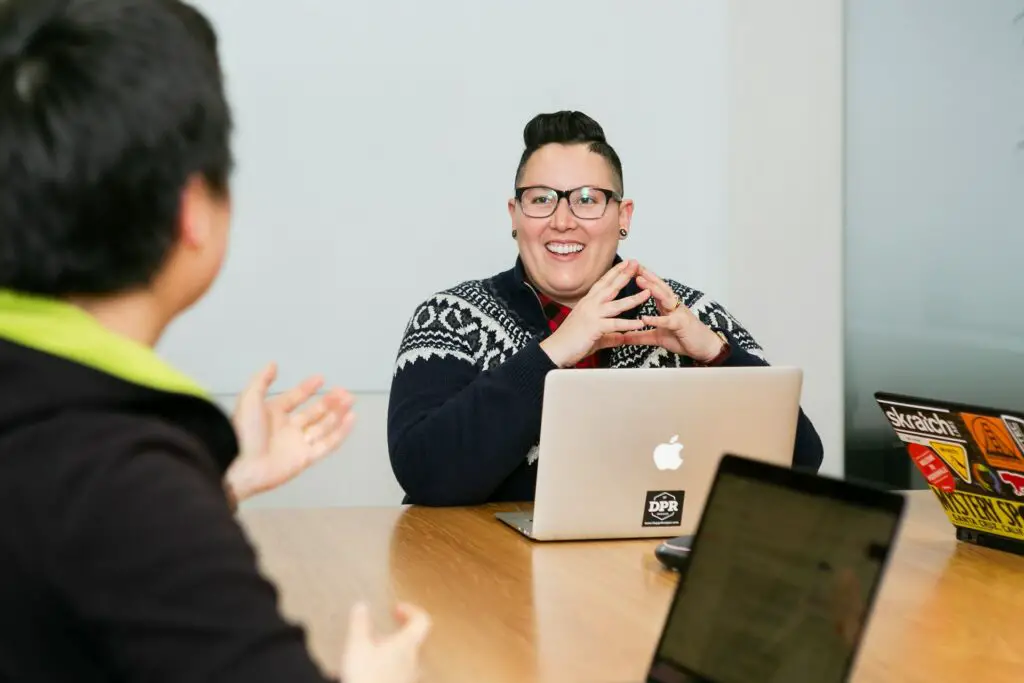 lgbtq-person-with-laptop-smiles-at-another-person-during-meeting