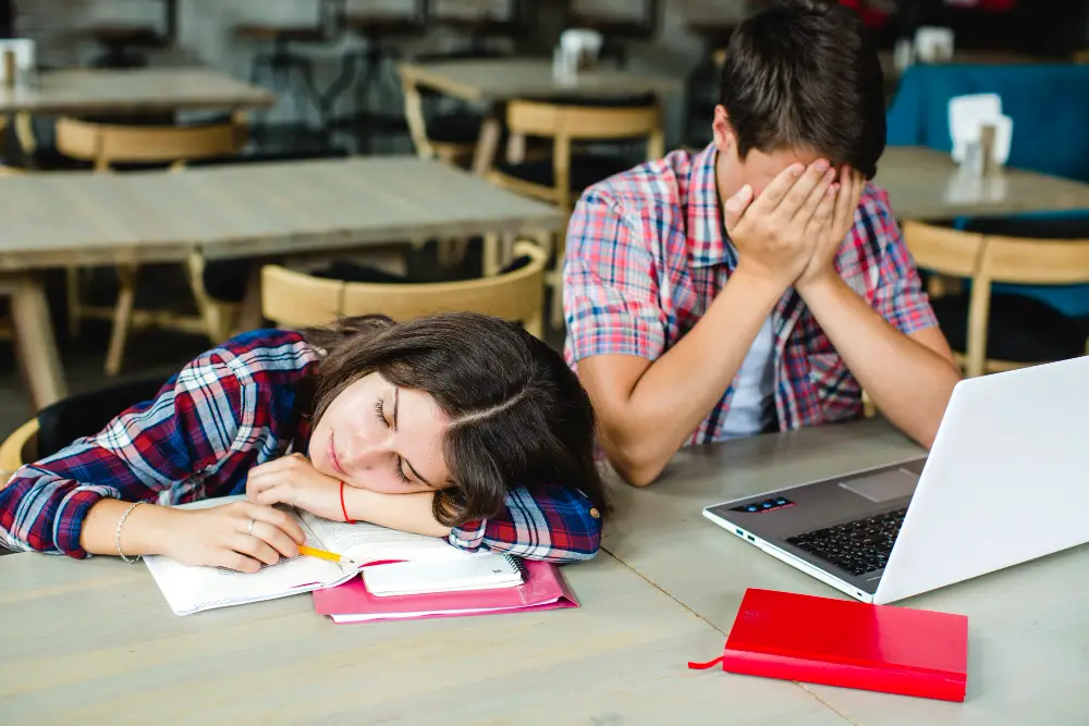 A couple of exhausted high school seniors after juggling homework and college applications to meet the early action deadline