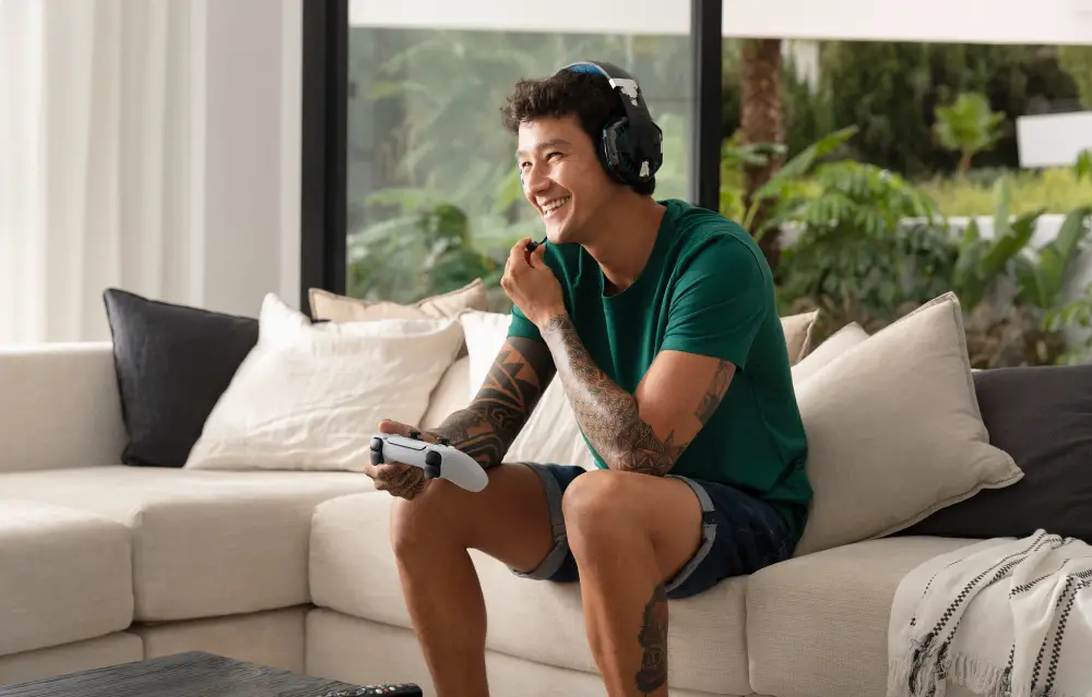 A happy and tattooed male college student plays a video game on the console