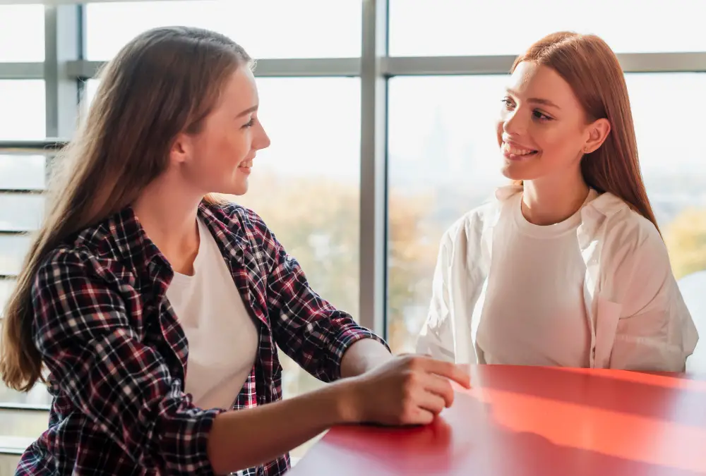 Two female college friends sharing internship interview tips and practicing for it