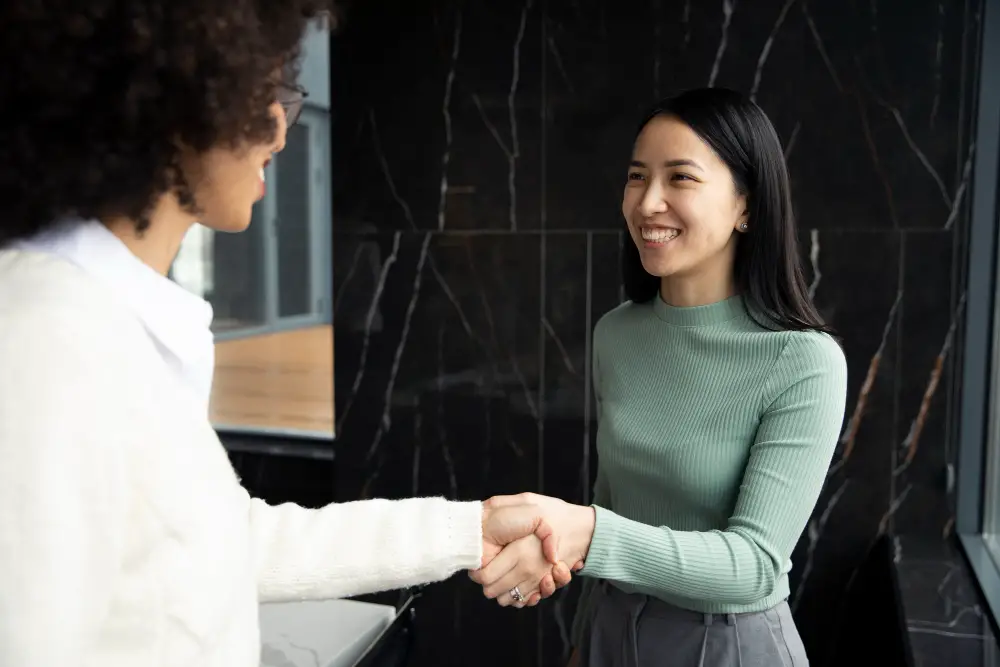 An Asian-American female college applicant thanks the internship interviewer with a handshake