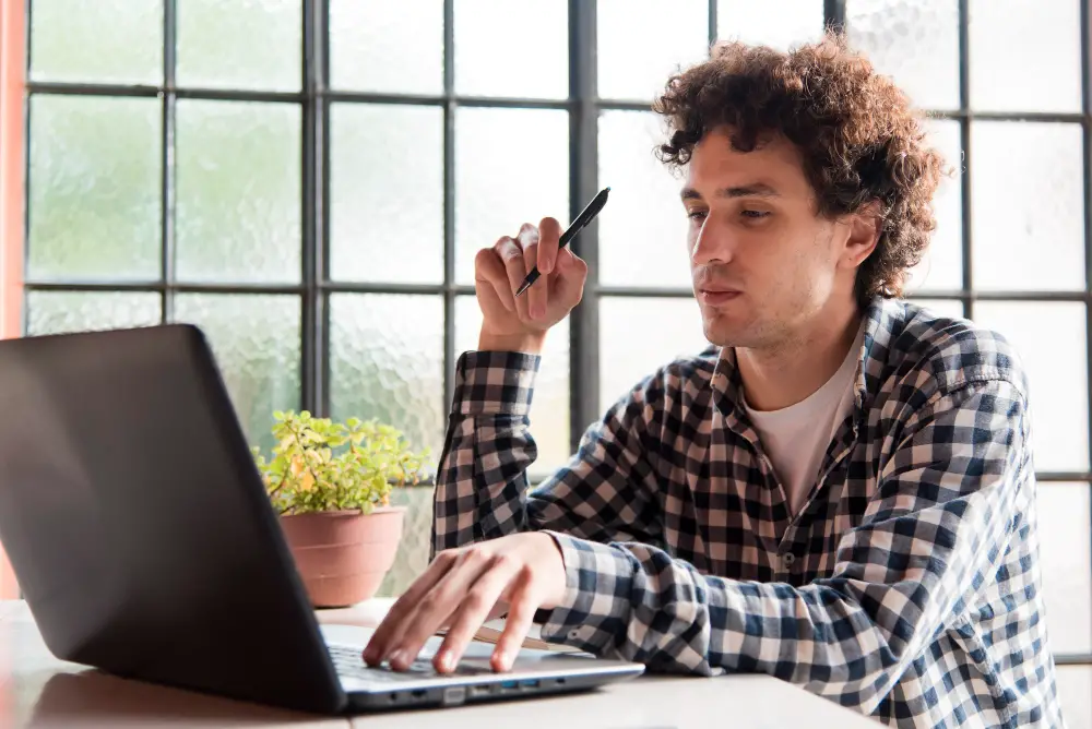 A curly-haired male college student fills up the online application for student loan consolidation for repayment