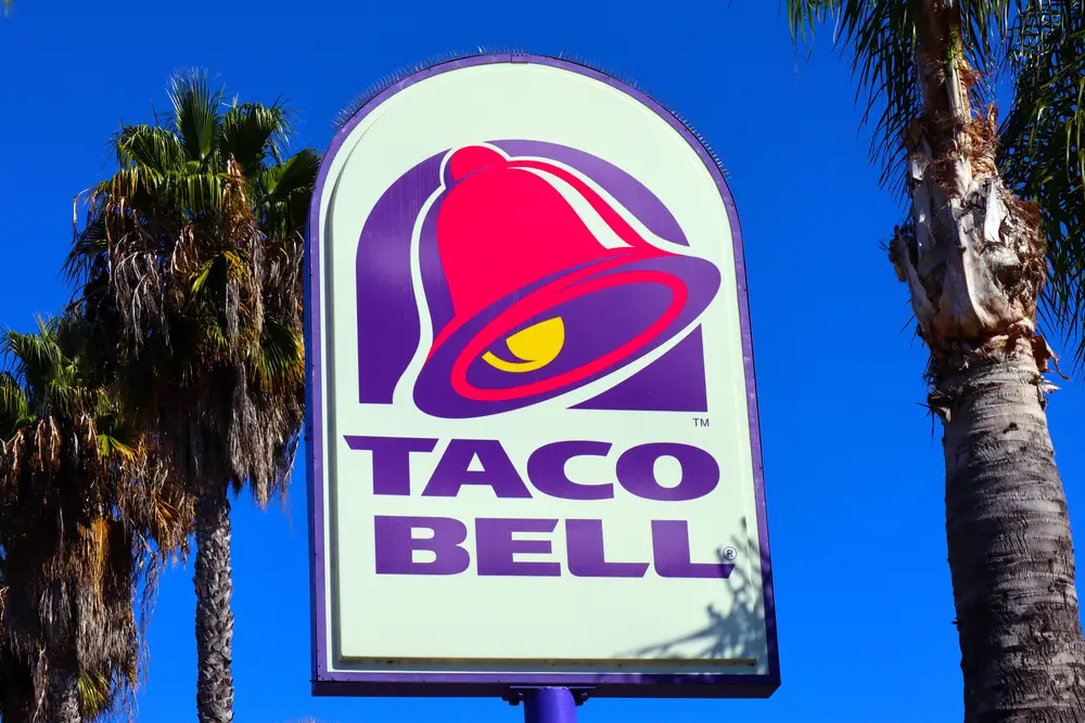 A Taco Bell store logo against three palm trees and the sky in Los Angeles, California