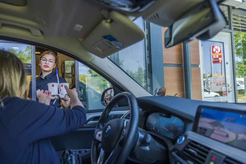 A part-time college student gives the customers drink orders via Mcdonald's drive through