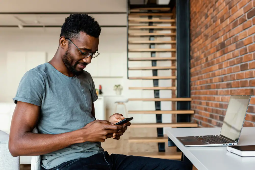 An African-American male international student studying abroad opens a Xoom account via the mobile app to send and receive money