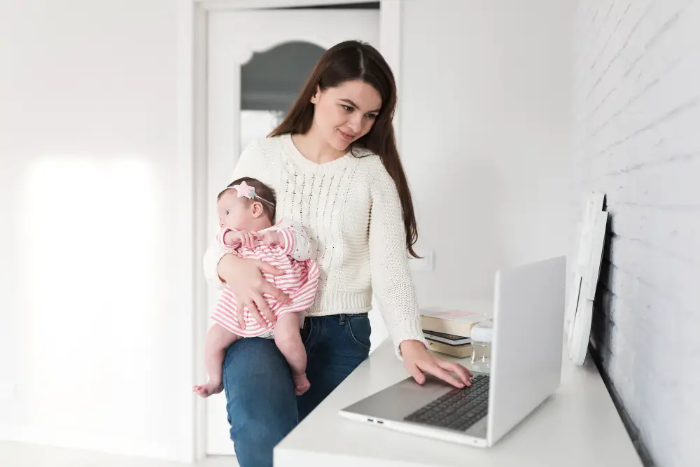 A single mother carrying her baby checks her laptop for her college's announcements of benefits regarding student parents