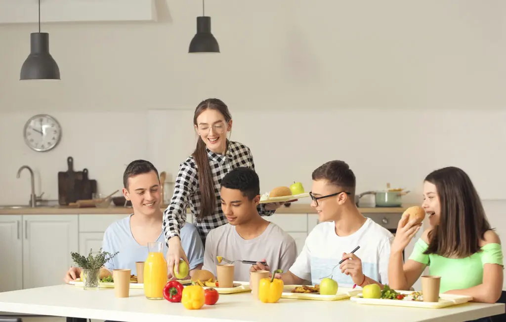 A diverse group of college students gathered around a table, enjoying a meal together with the best college food