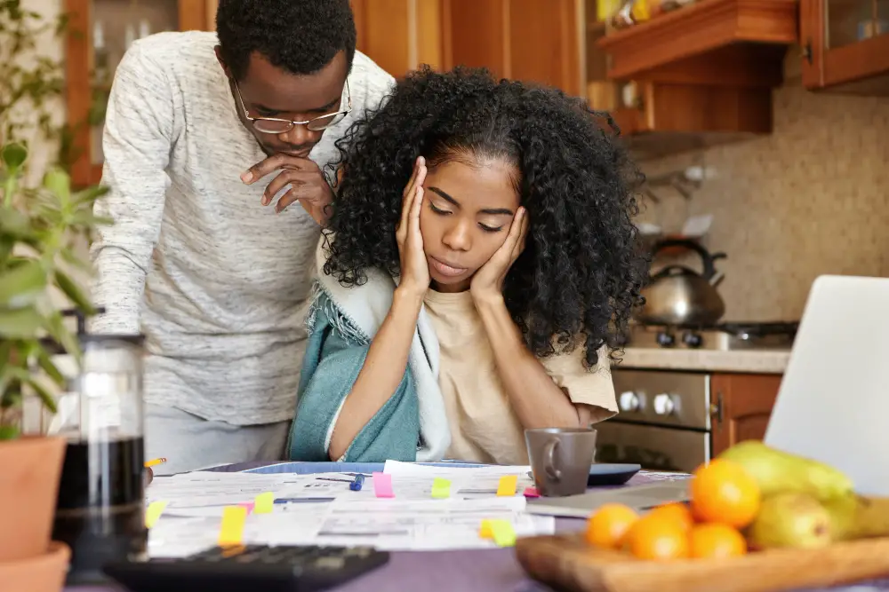 A couple of African-American siblings and first-generation college students confused about college application and financial aid forms laid out on their kitchen table