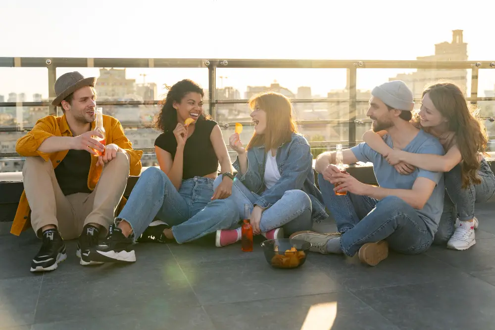 Five happy college students hang out on a balcony during sunset to unwind after a stressful exam week