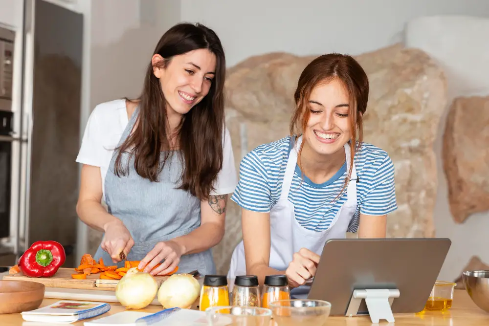 Two female friends chop veggies and prepare a meal as one of their ways to manage college stress