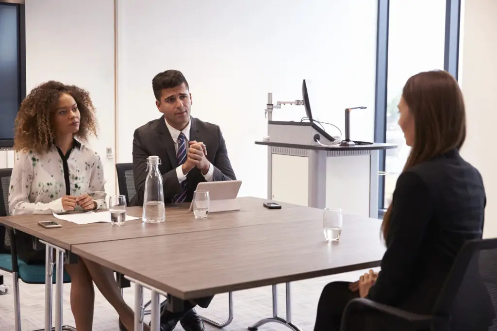 Mock interview with three individuals sitting around a table in an office
