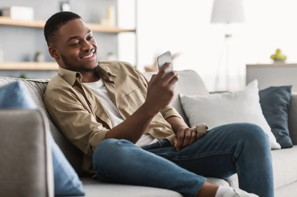 A young African American man sitting on a couch at home focused on building his online presence