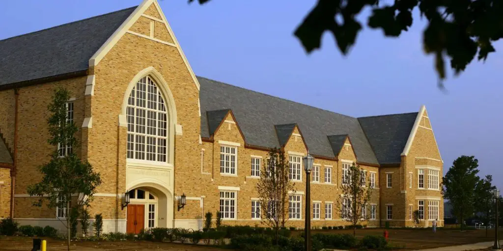 A brick building of a college with football scholarship with a big window, showcasing its grandeur and architectural design.
