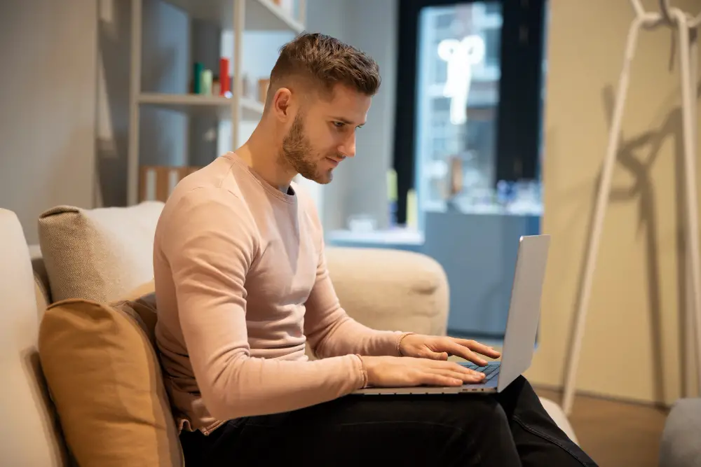 A male college student researches job market trends on his laptop to help him choose a career
