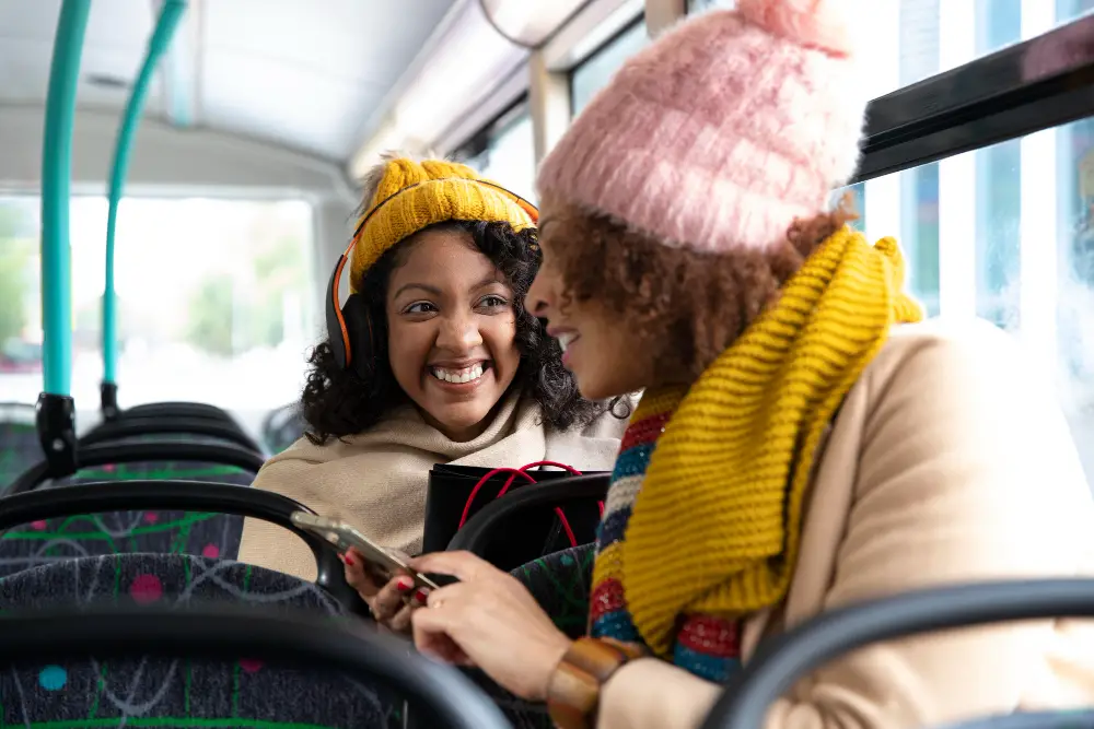 Two happy female college students riding the bus during winter