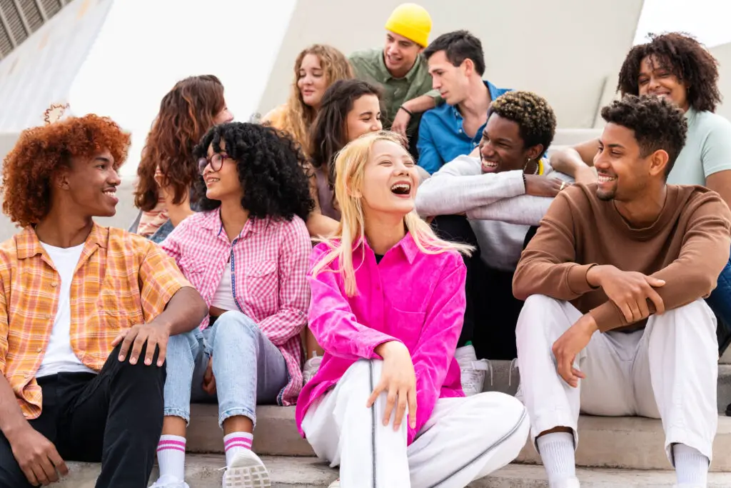 Young new college friends sitting on steps, sharing laughter and good times during icebreaker.