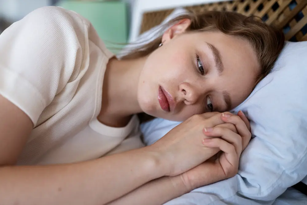 A female high school senior lying anxiously on her bed after receiving the news of college rejection