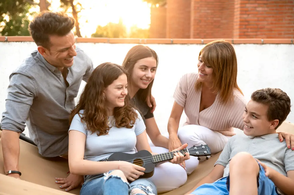 A family of five bonds by singing and playing the ukelele outdoors to comfort their teenage child who received news of college rejection