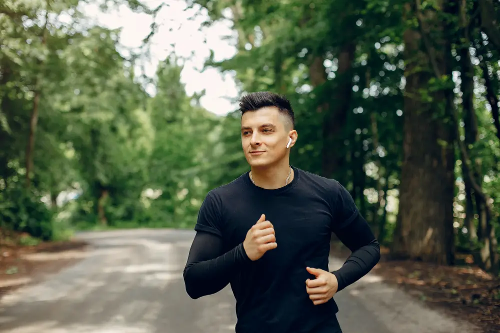 A happy and confident male college student running in the campus forest as his daily exercise