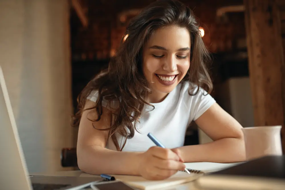 A happy female college student realizing the connection between concepts while note-taking