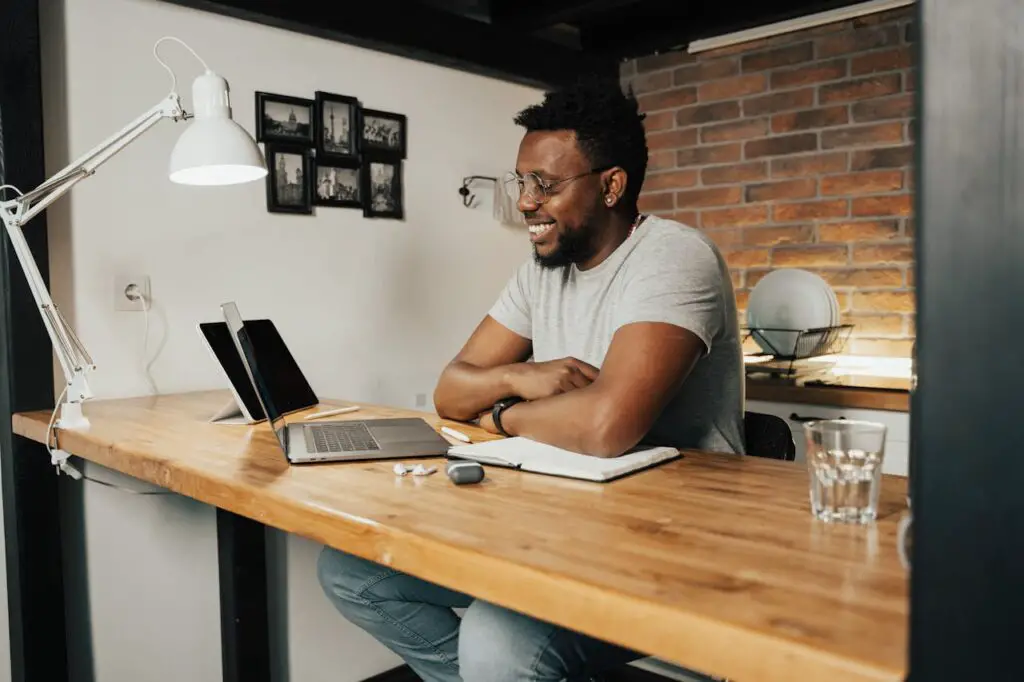 A male college student sitting at a desk with a laptop focused on his work