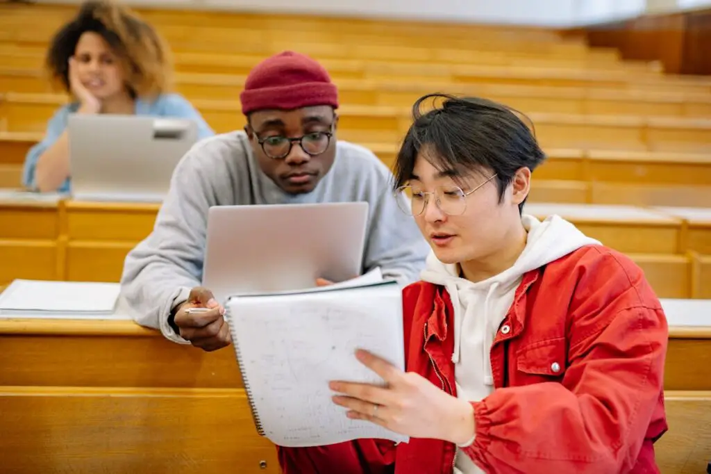 Two students in a lecture hall focused on reading about policy changes to complete college graduation requirements