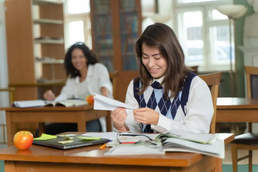 A woman sitting at a desk holding a a paper airplane