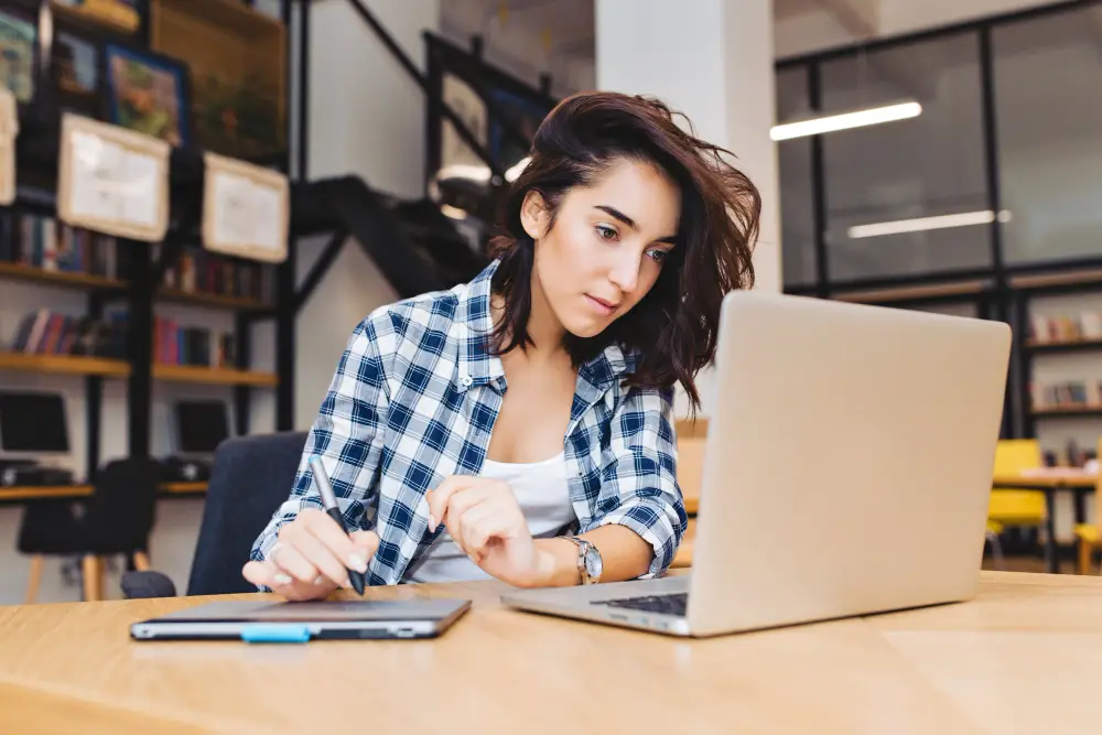 A female college student focuses on searching for undergraduate research opportunities online at the campus library