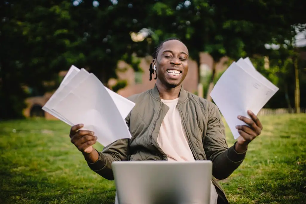 A college student sitting outdoors with research papers hoping to avoid plagiarism