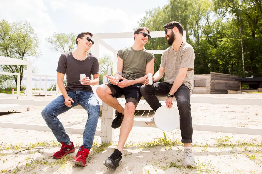 Three fraternity brothers drinking and laughing at the beach