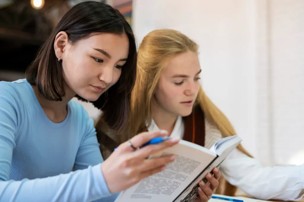 A pair of female college students writing journals for their writing class.